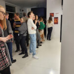 Zdjęcie z wernisażu wystawy iLand Małgorzaty Mikołajczyk. Goście galerii rozmawiają i oglądają prace.