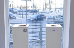 Przeszklone ściany galerii. Widok na parking