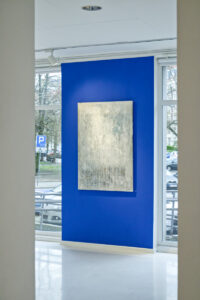 Sala wystawiennicza. Za przeszklą ścianą galerii widok na parking
