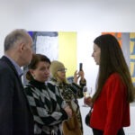 Wernisaż wystawy "Paint and Print?". Grupa ludzi rozmawia i podziwia prace.