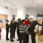 Wernisaż wystawy "Paint and Print?". Grupa ludzi rozmawia i podziwia prace.