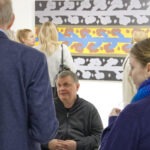 Wernisaż wystawy "Paint and Print?". W kadrze rozmawia prof. Rysiński, mężczyzna i kobieta. W tle grupa ludzi rozmawia i podziwia prace.