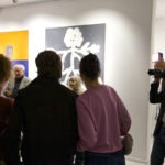 Wernisaż wystawy "Paint and Print?". Grupa ludzi rozmawia i podziwia prace.