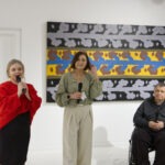 Wernisaż wystawy "Paint and Print?". W kadrze przemawiająca do mikrofonu kierowniczka Apteki Sztuki Katarzyna Soboń. Obok koordynatorka Magdalena Krowicka i artysta prof. Rysiński.