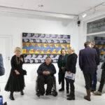 Wernisaż wystawy "Paint and Print?". W kadrze prof. Rysiński rozmawia z dwoma kobietami. Po bokach rozmawiający i podziwiający prace ludzie.