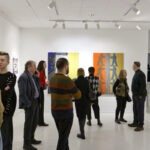 Wernisaż wystawy "Paint and Print?". W kadrze grupa rozmawiających i podziwiających prace ludzi.