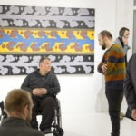 Wernisaż wystawy "Paint and Print?". W kadrze prof. Rysiński rozmawia z mężczyzną.