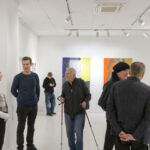 Wernisaż wystawy "Paint and Print?". Grupa ludzi rozmawia i podziwia prace.