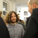 Wernisaż wystawy "Świątynia Gochos". Na pierwszym planie rozmawijący artysta Krzysztof Ostrzeszewicz i mężczyzna.