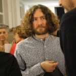 Wernisaż wystawy "Świątynia Gochos". Na pierwszym planie rozmawijący artysta Krzysztof Ostrzeszewicz i mężczyzna.